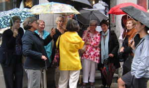 A small crowd of people standing outside with umbrellas