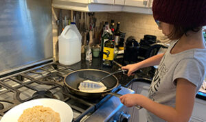 A child cooking pancakes.